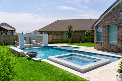 Luxury backyard with resort-style swimming pool, spa, and brick home with manicured lawn