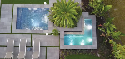 Aerial view of luxury residential property with two swimming pools, lounge chairs, and tropical landscaping