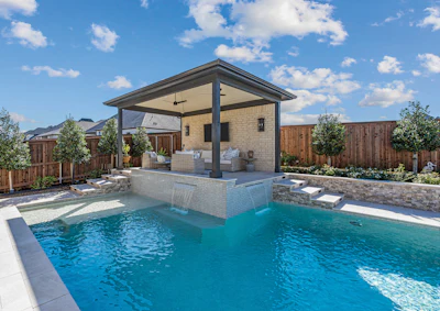 Modern backyard with turquoise swimming pool, brick poolhouse with covered patio, and wooden fencing