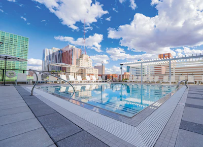 Rooftop swimming pool overlooking urban cityscape with modern high-rise buildings and blue sky