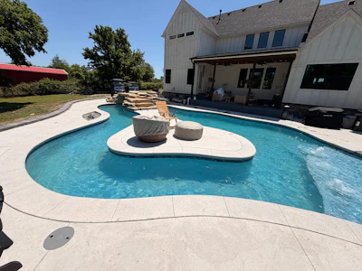 Luxury backyard with resort-style swimming pool, spa, and modern home featuring stone patio and lounge seating