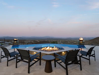 Luxury outdoor patio with fire pit, pool, and mountain valley views at dusk