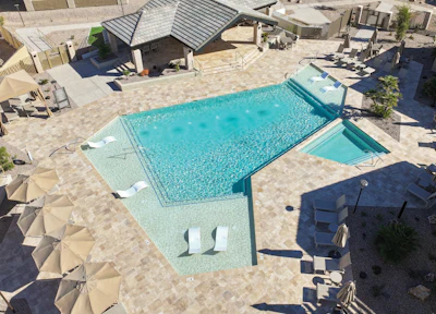 Aerial view of luxury resort pool with turquoise water, lounge chairs, umbrellas, and beachside cabana