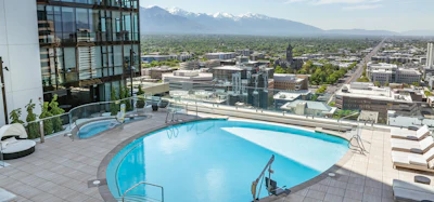 Luxury rooftop pool overlooking downtown city skyline with snow-capped mountains in the distance
