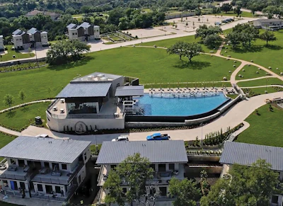 Aerial view of luxury estate with resort-style pool, multiple residential buildings, and manicured grounds