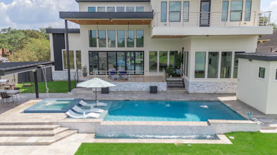 Modern luxury home with resort-style pool, spa, and manicured lawn overlooking contemporary architecture