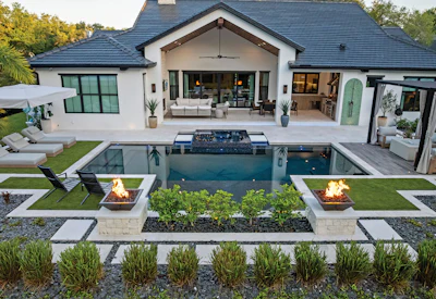 Modern luxury home with pool, fire pits, and manicured lawn overlooking contemporary architecture
