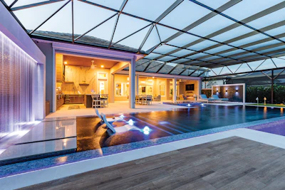 Modern luxury home with indoor swimming pool, glass ceiling, and illuminated interior spaces at dusk