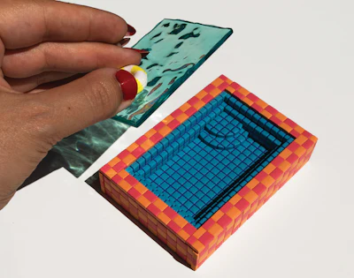 Hand holding colorful pixelated 3D blocks with turquoise and coral geometric patterns