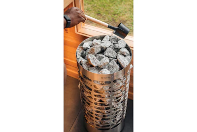 Person using a chimney starter filled with hot charcoal briquettes for outdoor grilling preparation