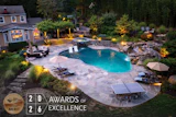Luxury backyard pool with stone patio, ambient lighting, and 2026 Awards of Excellence merit badge