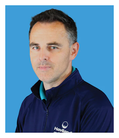 Professional headshot of a man wearing navy Haviland jacket against blue background