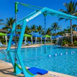 Turquoise pool hoist with Aquazion branding at a resort pool with palm trees and lounging areas