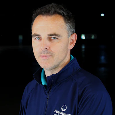 Professional portrait of man wearing navy Haviland jacket against dark background