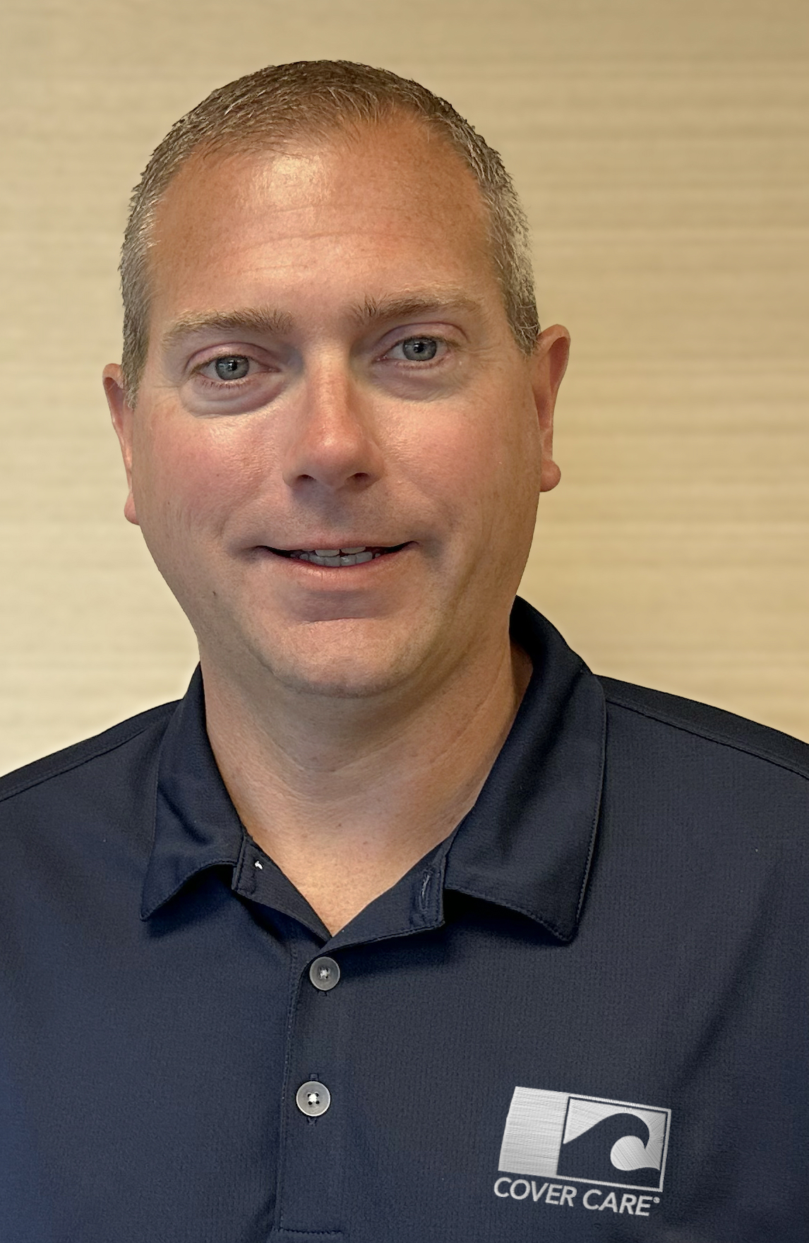 Professional headshot of a man wearing a navy Cover Care polo shirt against a neutral background