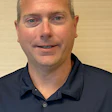 Professional headshot of a man wearing a navy Cover Care polo shirt against a neutral background