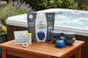 Hot tub maintenance product kit displayed on wooden table with spa in background and garden landscaping